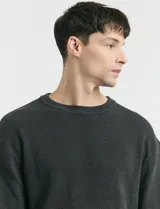 Sweater de punto en color negro, con cuello redondo, mangas largas y puños acanalados.