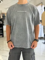 Remera oversize gris con efecto gastado, mangas cortas y estampa con texto blanco en el frente y en la espalda.