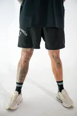 Short deportivo negro con aberturas laterales, confeccionado en tejido técnico. Presenta una estampa gráfica en color gris con la frase 'Vincit qui se vincit' y el número '1:17' junto al logo de la marca.
