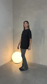 Conjunto compuesto por un remerón negro de corte holgado con aberturas laterales y un pantalón de tiro alto con diseño acampanado y estampado de lunares blancos sobre fondo negro.