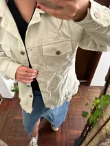 Campera de jean color verde lima, de corte oversize, con bolsillos frontales con solapa, cierre de botones metálicos y ruedo deshilachado.