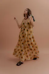Vestido largo de tirantes finos, con escote en V y estampado de girasoles sobre fondo beige.