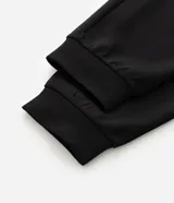 Pantalón jogger de pijama color negro, confeccionado en tejido de modal con mezcla de poliéster y elastano. Presenta cintura elástica con cordón de ajuste, bolsillos laterales y puños ajustados en el ruedo.