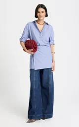 Vestido camisero corto de algodón en color celeste con finas rayas blancas, con diseño asimétrico tipo wrap, mangas largas y escote en V con cuello camisero.