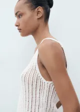 Top de crochet color blanco, sin mangas, con cuello escotado y tirantes anchos.