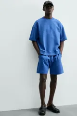 Bermuda de algodón color beige claro, corte relajado (relaxed fit), con cintura elástica ajustable mediante cordón y bolsillos laterales y trasero de plastrón.