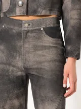 Pantalón de cuero ovino distress color negro, de silueta ancha con recortes diagonales y curvos en delantero y espalda, bolsillos frontales y bolsillos plaqué en la parte trasera.