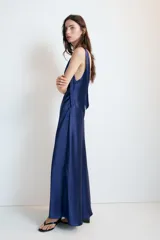 Vestido midi satinado color marrón, con escote en V y tirantes anchos ajustables con lazada en los hombros. Presenta cierre lateral con cremallera oculta.