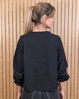 Camisa blanca de manga larga con volados en el escote en V y en los puños, con cierre frontal de botones oscuros.