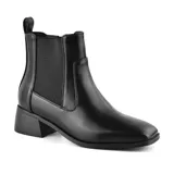 Bota corta negra de cuero sintético, con elástico lateral, punta redondeada y taco bajo.