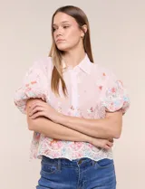 Camisa de gasa rosa con estampado floral y bordados, cuello camisero, mangas cortas abullonadas y cierre frontal de botones.