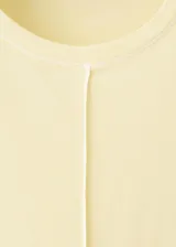Remera de algodón color amarillo claro, con mangas cortas, cuello redondo y costuras visibles a contratono en la parte frontal y laterales.