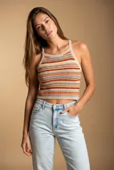 Top tejido de punto con diseño a rayas horizontales en tonos tierra, naranja y crema. Presenta un corte al cuerpo, escote halter y breteles finos.