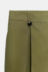 Pantalón de tiro alto con corte recto, bolsillos delanteros y detalle de pinzas con botones en la cintura. Cuenta con cierre frontal de cremallera y gancho metálico.
