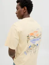 Remera color crema de algodón con cuello redondo, manga corta y estampado en la espalda con un paisaje costero.