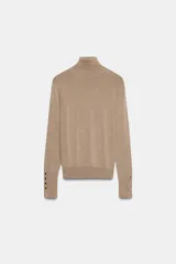 Jersey de punto liso en color beige, con cuello alto y manga larga con detalle de botones metálicos en los puños.