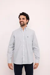Camisa de corte clásico confeccionada en algodón, con diseño de rayas verticales en tonos claros, cuello abotonado y manga larga. Presenta un pequeño bordado en el pecho.