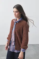 Cardigan de textura suave y efecto fluffy, color beige, con cuello redondo, cierre frontal con botones y puños acanalados.