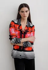 Camisa de manga larga con cuello solapa y cierre frontal de botones. Presenta un diseño estampado con bloques geométricos en tonos azul, blanco y negro.