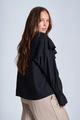 Blusa de color marrón con escote en V, mangas largas abullonadas con puños elásticos y detalles de volados en los hombros y el frente.