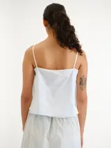 Blusa celeste claro con tirantes finos, escote en V y diseño abierto al frente con lazos para atar.