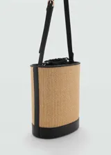 Bolso tipo bucket con cuerpo de rafia y base, bordes y correa ajustable en color negro. Presenta un diseño estructurado de tamaño mediano con cierre regulable.