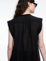 Camisa negra sin mangas con cuello mao y cierre frontal con botones.