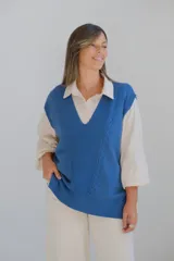 Chaleco de punto color celeste con escote en V, diseño trenzado en los laterales y terminaciones acanaladas en el ruedo y las sisas.