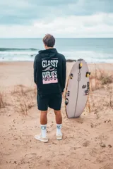 Hoodie negro de corte oversize, con capucha y estampa gráfica en la espalda con la inscripción "GLASSY WAVES" en tonos blancos y rosados.