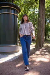 Camisa de corte clásico con estampado de rayas verticales en tonos blanco y marrón. Presenta cuello camisero, cierre frontal con botones y mangas largas con puños rectos. Confeccionada en tela liviana con caída suave.