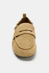 Mocasín de serraje color tostado, con copete subido, antifaz en la parte delantera y detalle fruncido en la parte trasera con tirador y aplique metálico.