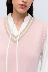 Chaleco de punto color beige con escote en V y ribete blanco.