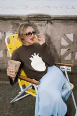 Buzo de algodón color marrón oscuro con estampado frontal de un corazón blanco. Tiene cuello redondo y mangas largas.