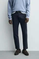 Pantalón chino de corte ajustado, color beige, con bolsillos laterales y bolsillos traseros de vivo. Cuenta con cierre frontal de cremallera y botón.