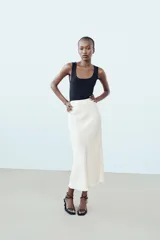 Camiseta blanca ajustada de poliamida con tirantes anchos y escote redondo.