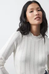 Polera de tejido de punto con textura calada y diseño vertical acanalado. Presenta cuello levemente alto, mangas largas y silueta entallada.