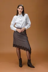 Falda midi de corte asimétrico en color marrón con patrón de cuadros. Presenta un diseño ajustado en la cadera con un bajo irregular decorado con encaje en el borde.