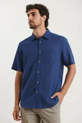 Camisa sport de manga corta, confeccionada en una mezcla de lino y algodón. Presenta cuello clásico, cierre frontal con botones de coco y un bolsillo aplicado en el pecho.