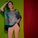 Remera poncho de corte amplio con estampado de hojas en tonos verde, gris y rosa.