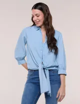 Camisa de lyocell color celeste, con cuello camisero, cierre frontal con botones y detalle de nudo en el ruedo. Presenta mangas tres cuartos abullonadas con puños elásticos.