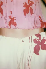 Top sin mangas color rosa con estampado de flores rojas, cuello halter y espalda descubierta.