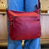 Bandolera de cuero sintético color mostaza, con dos bolsillos frontales con cierre, apertura superior con cierre, división interna y bolsillo trasero con cierre. Incluye correa larga regulable combinada en tonos mostaza y beige.