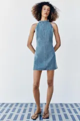 Vestido corto de denim con cuello halter, espalda descubierta y diseño de lavado combinado en tonos de azul.
