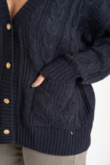 Cardigan de punto texturado con diseño de ochos, color azul marino, con escote en V, cierre frontal con botones dorados y mangas largas con puños acanalados.