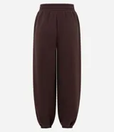 Pantalón estilo aladín de corte amplio y holgado, color marrón chocolate. Confeccionado en tejido de moletón con felpa interna, cuenta con cintura elástica y puños elásticos en los tobillos.