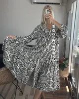 Vestido largo marrón con estampado de hojas, cuello camisero, mangas largas y corte escalonado.