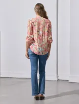 Blusa de gasa estampada con flores en tonos rosa, amarillo y azul. Tiene cuello a la base, escote en V y botones. La delantera tiene detalle plisado y las mangas son 3/4 regulables con presilla y botón.