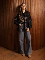 Camisa de manga larga con diseño de terciopelo estampado con motivos florales y paisley, combinada con paneles de tela transparente en la parte superior. Presenta cuello clásico, cierre frontal con botones y mangas abullonadas.