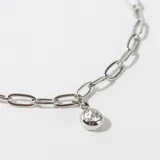 Pulsera de eslabones alargados plateados, con un pequeño dije de cristal redondo colgante. Posee cierre de mosquetón y cadena de ajuste.