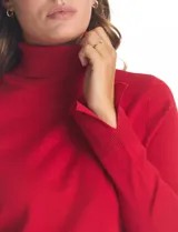 Polera de tejido fino, color rosado, con cuello alto, manga larga y detalle de tajo en los puños.